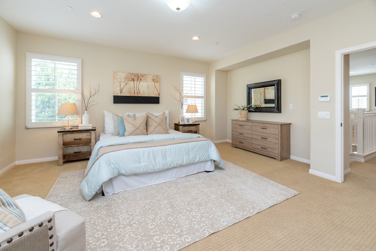 A neutral bedroom with warm tones, artwork above the bed, and soft natural light