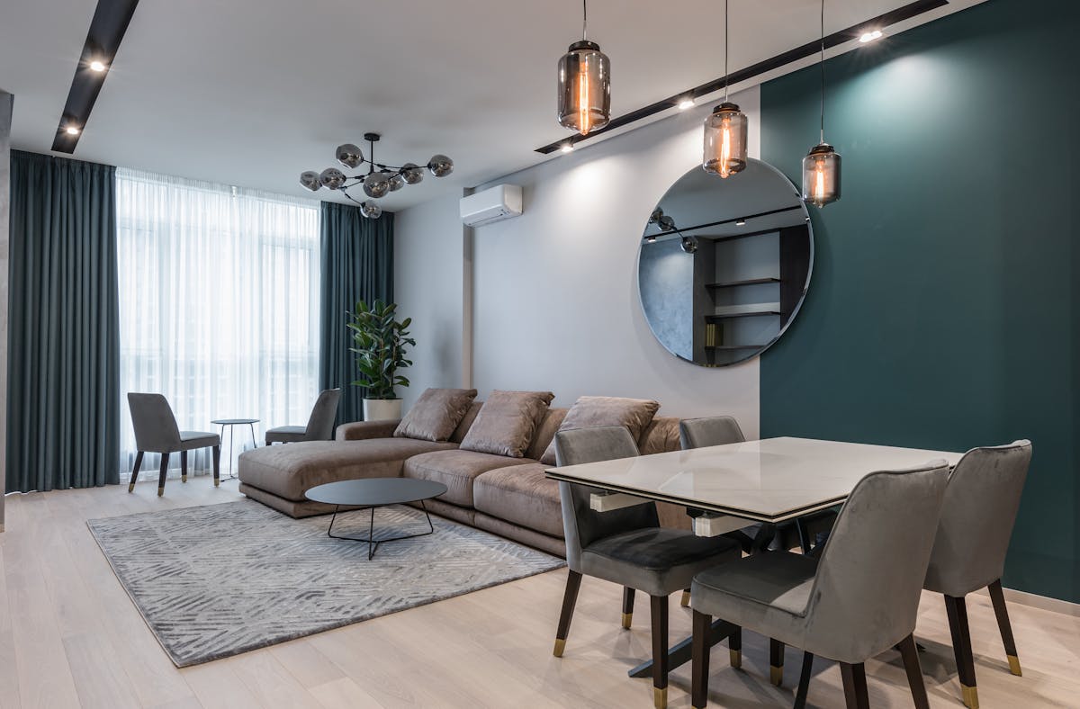 A modern apartment living room with a sofa, rug, and round mirror